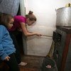 In their Olenivka settlement house in the non-government controlled area of Donetsk region, 11-year old Alika and her six-year old sister Sofia add coal to the stove.