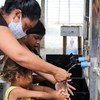 A woman and children use new handwashing facilities installed by UNICEF in Embratel, an informal urban settlement in Boa Vista, in northern Brazil.