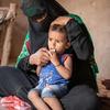 A woman sits with her son at the family's makeshift home in Lahj, Yemen.