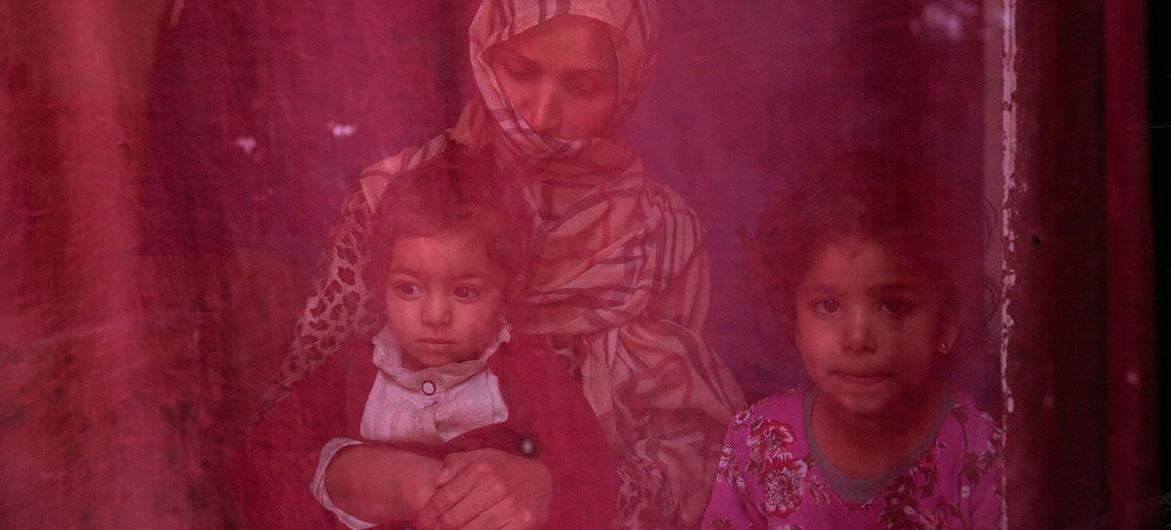 Now unemployed, a woman sits at home with her two daughters.