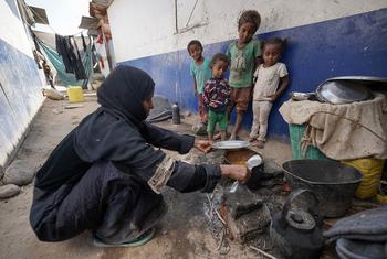 A mother-of-nine, who is suffering from malnutrition herself, cooks a meal for her children in an IDP camp in Aden, Yemen.