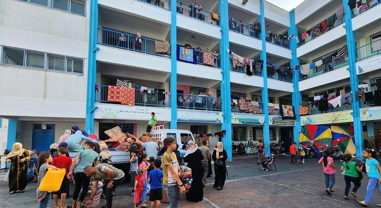 Families sheltering in an UNRWA school collect mattresses.