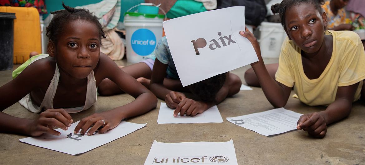 A schoolgirl in Port-au-Prince holds up a sign in French which reads 'peace'.