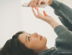 寝ながらスマホをする女性の写真