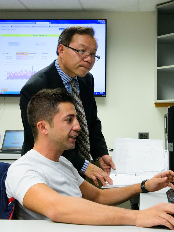 A student and professor look at a computer