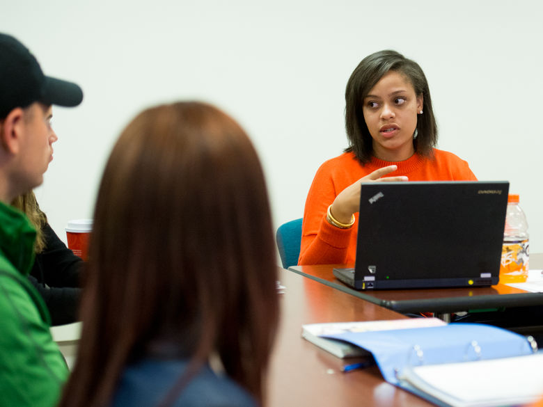 Students sitting at a table working on a laptop