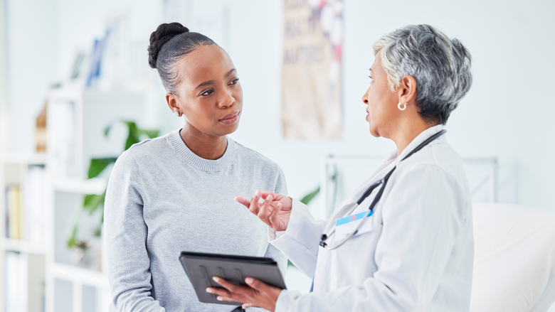 Doctor holding tablet speaking with a patient