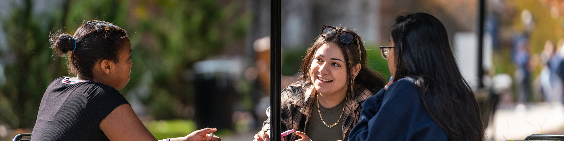 Female students seated at table outdoors on campus.