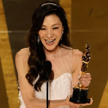 Michelle Yeoh holds an Oscar while onstage at the Academy Awards.