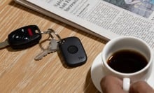 a tile tracker is attached to a keyring that sits on a tabletop next to a cup of coffee