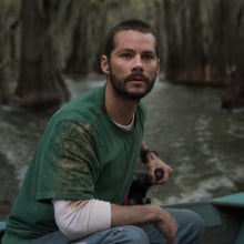 A man in a motorboat travels through a tree-filled lake.