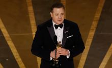 Man in a suit tearfully accepts an award on stage. 