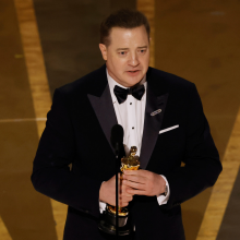 Man in a suit tearfully accepts an award on stage. 