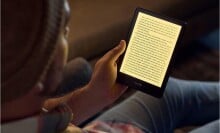 a person reads the kindle paperwhite in a dimly lit room