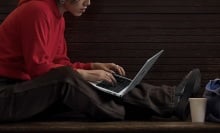 person sitting outside using macbook on their lap