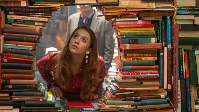 Máiréad Tyers looks through a hole in a wall of books in the TV series "Extraordinary."