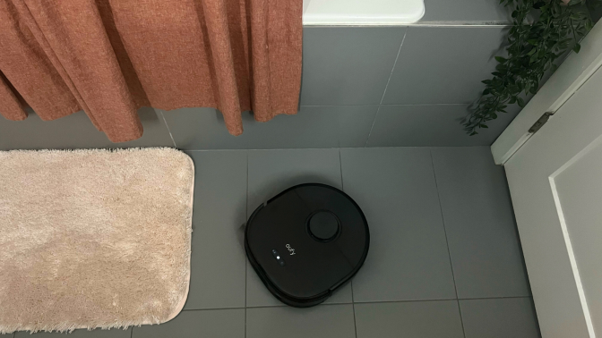 Eufy X10 Pro Omni robot vacuum mopping tile floor in bathroom near shower and bath mats