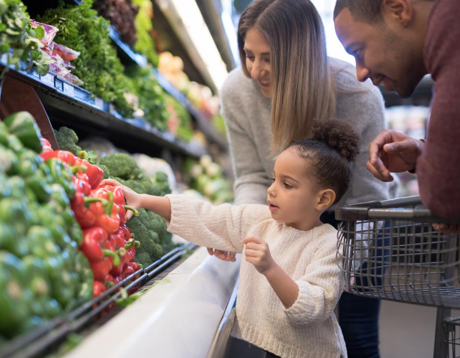 A family grocery shopping in the produce section.