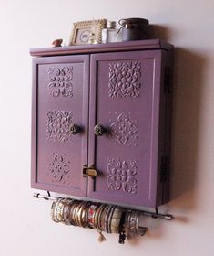 a purple cabinet mounted to the side of a wall with bracelets hanging on it