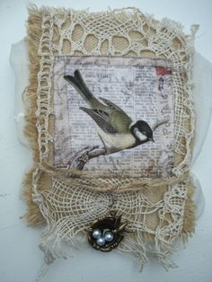 a bird is sitting on top of a piece of fabric with lace and beads around it