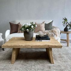 a living room with a couch, coffee table and two vases filled with flowers