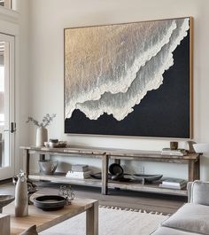 a living room filled with furniture and a large painting on the wall over a coffee table