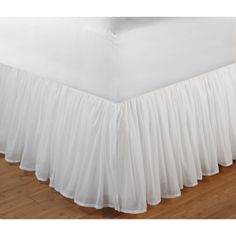 white bed skirt with ruffled edges on wooden floor