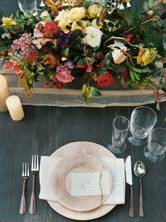 the table is set with plates, silverware and flowers in an old wooden box