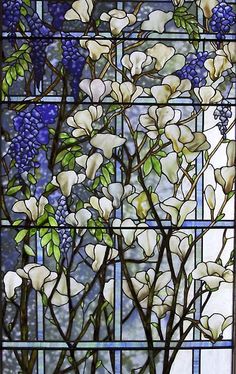 a stained glass window with white flowers and green leaves on it's side, in front of a blue background