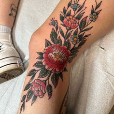 a woman's arm with flowers and leaves tattooed on her left arm, sitting in a chair