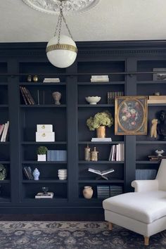 a white chair sitting in front of a black book shelf filled with lots of books