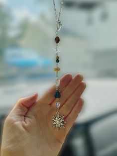 a person holding their hand up in the air with a necklace hanging from it's palm