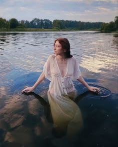 a woman is sitting in the water with her legs spread out and looking up at the sky