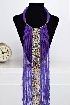 Unique Africa Maasai Handcrafted Beaded Necklace with an Elegant Look and Brilliant Finish.Color = Purple and Multi-Color Beads.Length (Around Neck) = 17 Inches / 43 Centimeters.Length ( Downwards ) = 14.5 Inches / 37 Centimeters.**GET FREE SHIPPING FOR ADDITIONAL ITEMS PURCHASED.Yes, Buy Multiple Items and pay shipping for 1 item only- The rest ships Free. (No Limits on the number of Multiple items). With a faster delivery time of 3 days via DHLExpress, Worldwide. Ordinary/Standard Shipping als Purple Beaded Chain Necklace With Round Beads, Purple Beaded Long Necklace, Long Purple Beaded Necklaces, Purple Necklaces With Dangling Round Beads, Purple Large Beaded Necklace, Purple Handmade Bohemian Necklaces, Purple Necklaces With Dangling Beads, Purple Beaded Necklaces For Party, Handmade Purple Bohemian Necklaces