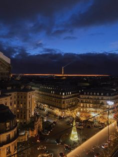 an aerial view of a city at night with lights and buildings in the foreground