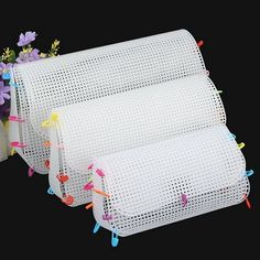 three pieces of white perfored paper with colorful pins and flowers on them, sitting next to each other