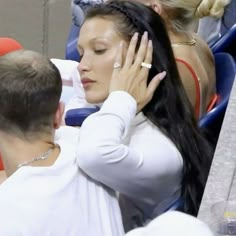 a woman sitting in the stands with her hand on her head and another man standing next to her