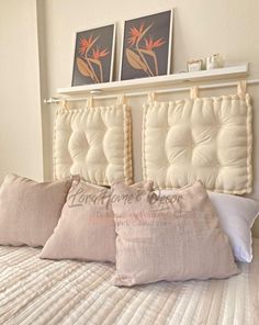 two pillows are sitting on the bed in front of some framed pictures and artwork above it