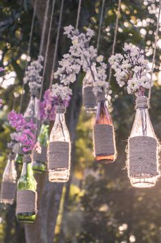 several bottles filled with flowers hanging from strings