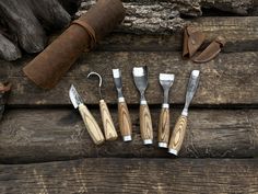 the tools are laid out next to each other on the wooden table with leather sheaths