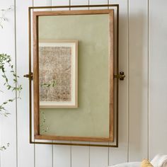 a mirror hanging on the wall next to a pillow and potted plant in front of it