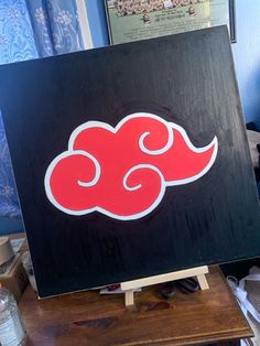 a black and red painting on top of a wooden table next to a blue wall