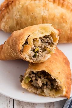 two meat filled pastries on a white plate