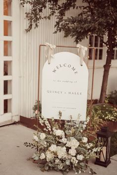 a welcome sign with white flowers and greenery