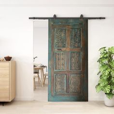 an old wooden door is opened to reveal a dining room with a potted plant