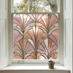 a window that has some kind of art glass in front of it and a potted plant next to it