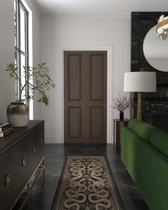 a green couch sitting in front of a wooden door next to a large rug on top of a black floor