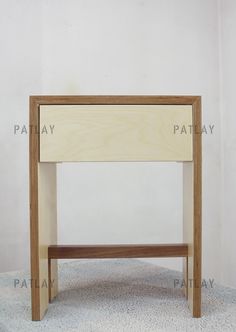 a small wooden table sitting on top of a carpeted floor next to a white wall