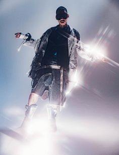 a man standing on top of a skateboard under a blue sky with lights behind him