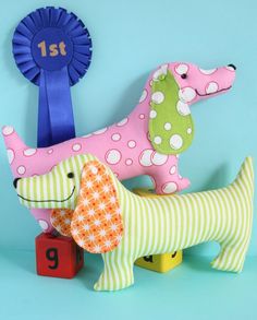 a stuffed toy dog sitting on top of a wooden block next to a blue ribbon